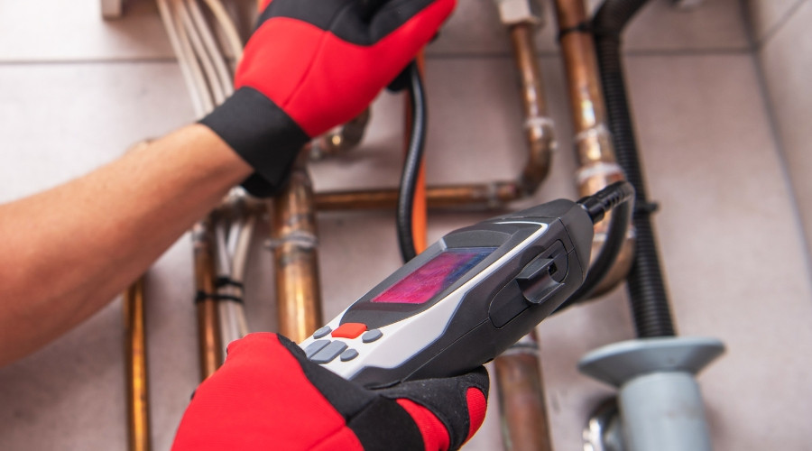 Plumber using a gas leak detector on plumbing pipes, highlighting safety measures for identifying dangerous gas leaks.
